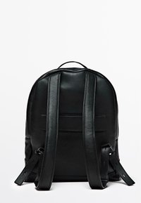 Zaino in pelle nera con forma arrotondata, cuciture visibili e spallacci regolabili. Presenta una maniglia superiore e un design minimalista.