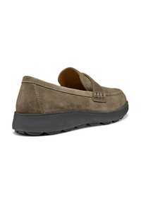 Zapato de ante marrón sin cordones con puntera redondeada, detalle de banda elástica y una suela de goma negra con un patrón de agarre texturizado.