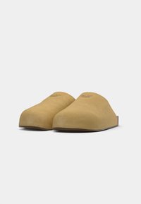 Brune mockasklær i semsket skinn med mandelformet tå og slip-on design; har en subtilt preg av merkevaren på fronten. Flat såle.