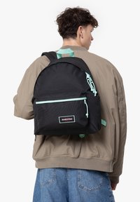 Czarny plecak Eastpak z miętowymi akcentami, z przednią kieszenią, regulowanymi paskami i teksturowanym wykończeniem materiału.