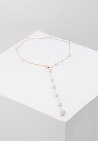 Collar en tono dorado con perlas blancas espaciadas uniformemente, que cuenta con una sección colgante que termina en una perla más grande. Diseño sencillo y elegante.
