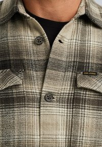 Geruite plaid shirt in neutrale tinten van beige en donkerbruin. Kenmerkt zich door twee borstzakken, zwarte knopen en een PME Legend label.