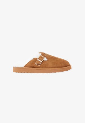 Pantofole in camoscio marrone con interno in pelliccia sintetica bianca, caratterizzate da un accentuo con fibbia argentata. Suola piatta e testurizzata per una presa migliore.