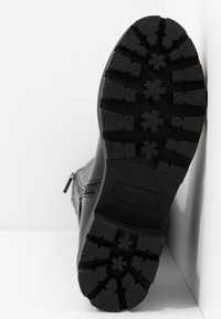 Černá kožená kotníková bota s drsnou, texturovanou gumovou podrážkou s hlubokým vzorem. Boční zip a velikost 37 vyznačená na podrážce.