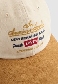 Beige and brown cap with embroidered text including "American legend," "Levi Strauss & co.," and "Levi's" logo patch on the front panel.