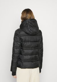 Schwarze Pufferjacke mit Kapuze, gestepptem Design und strukturiertem Material. Verfügt über lange Ärmel und elastische Bündchen.