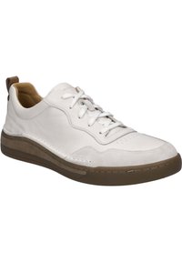 Weiße Leder-Sneaker mit Wildlederakzenten, brauner Gummisohle, abgerundeter Zehenform und traditioneller Schnürung; verfügt über eine Zuglasche an der Ferse.