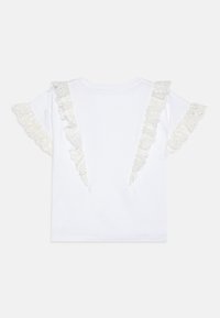 Camiseta blanca de manga corta con detalles de volantes de encaje en las mangas. Material de algodón suave con escote redondo y una textura lisa.