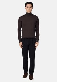 Čokoladno rjav turtleneck pulover v kombinaciji s črnimi prilagojenimi hlačami in rjavimi športnimi copati. Gladka struktura in prilega obliko.