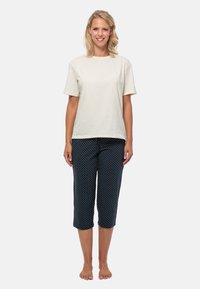 Kortärmad t-shirt i creamfärg av bomull som paras med marinblå capribyxor med vita prickar, slät textur, avslappnad passform och elastisk midja.