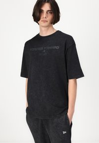 Black oversized t-shirt with a round neck, featuring "FOREVER FORWARD" printed in dark grey and a soft, worn texture.