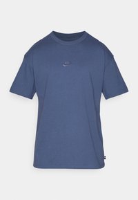 Modrá bavlněná tričko s krátkým rukávem a kulatým výstřihem. Má malé vyšívané logo Nike na hrudi. Jednoduchá barva, bez vzorů.