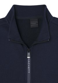Veste zippée marine en matière douce, avec un col haut, une doublure intérieure texturée et un zip argenté avec un logo.