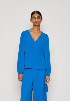 Blue wrap blouse with long balloon sleeves, textured fabric, deep V-neckline, paired with matching blue wide-leg trousers.