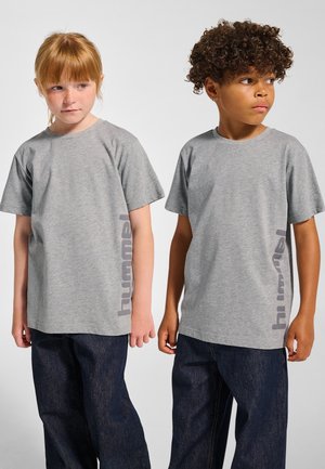 Grå T-shirts med korta ärmar har en subtil textur och en kontrasterande "hummel"-logotyp tryckt vertikalt i en mörkare grå nyans. Bärs med mörka jeans.