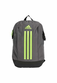 Grijze rugzak met drie verticale neon groene strepen, Adidas-logo aan de bovenkant, een voorvak met rits en verstelbare zwarte schouderbanden.