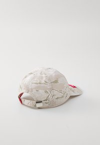 Căciulă bej cu camuflaj, cu o margine curbată, din material de bumbac, curea ajustabilă cu accesorii metalice și un patch cu logo roșu pe lateral.