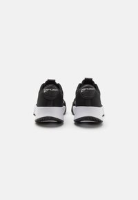 Scarpe sportive nere con tomaia in rete, una soletta bianca e una suola nera textured. Presentano un accento di marchio circolare sul tallone.