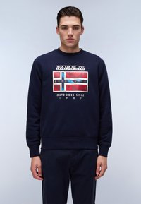 Sudadera azul marino con cuello redondo, que presenta un gráfico impreso de la bandera británica. El texto incluye "NAPAPIJRI" y "OUTDOORS SINCE 1987".