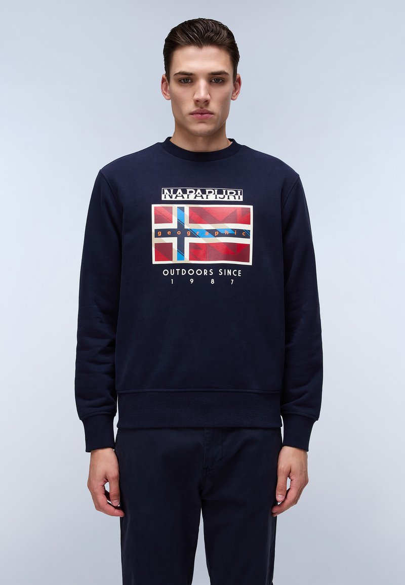 Sudadera azul marino con cuello redondo, que presenta un gráfico impreso de la bandera británica. El texto incluye "NAPAPIJRI" y "OUTDOORS SINCE 1987".
