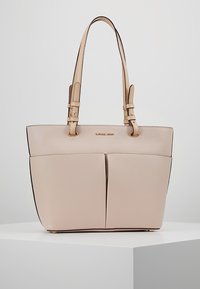 Różowa skórzana torba na ramię o sztywnej konstrukcji, z podwójnymi ramiączkami i dwiema przednimi kieszeniami. Posiada złote okucia i kontrastowe krawędzie.