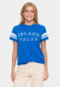 T-shirt en coton bleu avec des manches rayées blanches et le texte "ISLAND TALES" en lettres majuscules sur le devant.