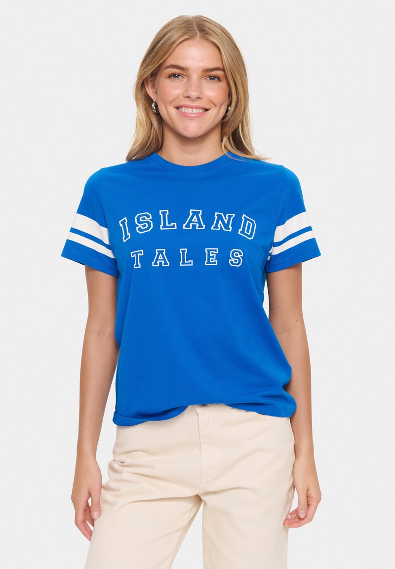 T-shirt en coton bleu avec des manches rayées blanches et le texte "ISLAND TALES" en lettres majuscules sur le devant.