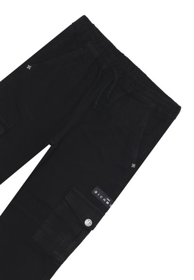 Pantaloni cargo neri con vita elastica, dettaglio con cordino, tasche laterali e un’etichetta con logo. Presentano una texture liscia e dettagli con bottoni.