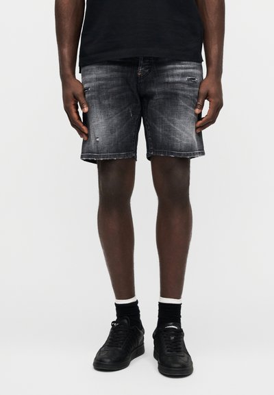 Temno sive denim kratke hlače z izpranim učinkom, detajli z obrabo in običajnim krojem. Nošene s črnimi supergami in nogavicami z belimi poudarki.