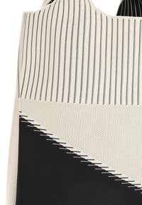 Canvas tas met gestreept ontwerp in beige en zwart, voorzien van een gestructureerd oppervlak en schuine geometrische patronen in contrasterende kleuren.