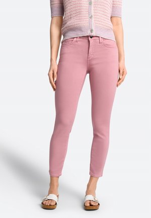Jeans rosa ajustados hechos de una mezcla de algodón; presenta cinco bolsillos, presillas para cinturón y un cierre con cremallera. El modelo lleva sandalias blancas tipo slide.
