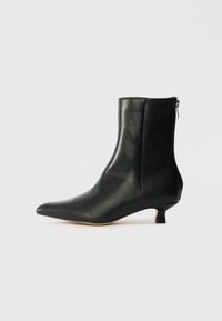 Bottine noire en cuir avec un bout pointu, une fermeture �éclair sur le côté et un petit talon courbé. Texture lisse et design élégant.