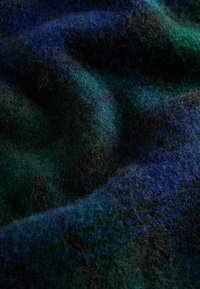 Wollstoff in Abstufungen von tiefblau und grün, mit einer weichen, strukturierten Oberfläche, die ein leicht gewelltes Muster und unterschiedlich lange Fasern aufweist.