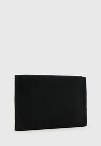 Clutch nera con un esterno in tessuto testurizzato, forma angolare e design minimalista. Non presenta hardware o abbellimenti visibili.