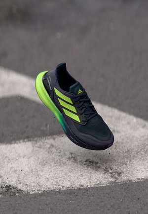 Sportschuh aus dunkelblauem Mesh mit leuchtend grünen Akzenten, strukturierter Sohle und Drei-Streifen-Logo. Verfügt über eine gepolsterte, gebogene Lightboost-Sohle.