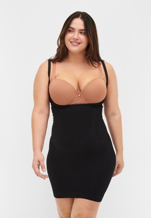 Abito bodycon nero con una texture a coste e spalline sottili, indossato sopra un reggiseno imbottito beige con un'accento in pizzo al centro.