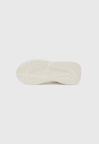Cream-colored sneaker sole with textured rubber, featuring a curved shape and patterned grooves for traction. "HUGO" logo embossed on side.