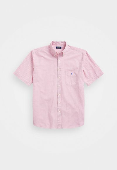 Sarkan un balts raibs krekls ar īsām piedurknēm, ar pogām aizvēršanu un kabatu; uz krūšu ir neliels logotips. Izgatavots no kokvilnas auduma.