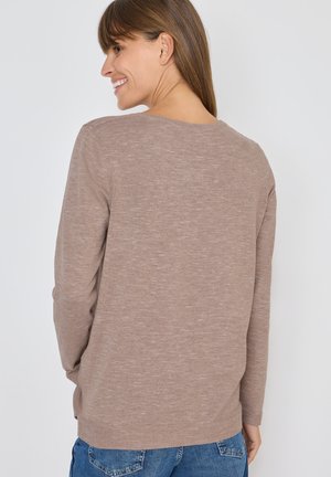 Langsleeve sweater in lichtbruin breiwerk, met een relaxte pasvorm, textuurafwerking en een ronde halslijn, gedragen met blauwe denim jeans.
