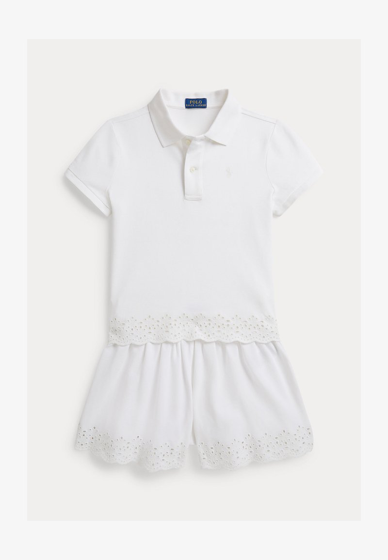 Λευκό φόρεμα πόλο με κοντά μανίκια, με κυματιστό τελείωμα και διακοσμητικά μάτια στο φούστα. Κατασκευασμένο από αναπνέον βαμβακερό ύφασμα.