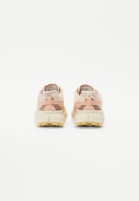 Chaussures de sport rose et beige avec tige en maille, semelle amortissante, accents texturés et semelle extérieure en caoutchouc durable. Conçues pour le confort et le soutien.