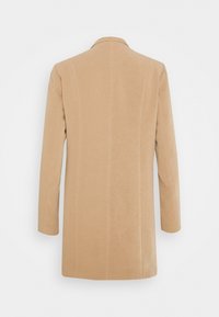 Blazer beige à manches longues avec une coupe droite, vu de dos, avec un col simple et des détails de coutures verticales.