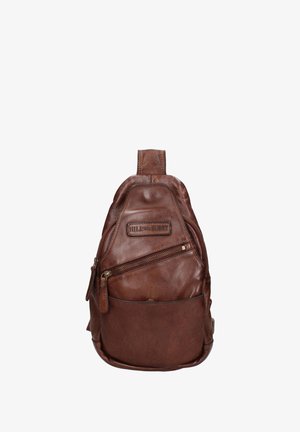 Sac à dos en cuir brun avec une forme courbée, une poignée supérieure, une poche zippée à l'avant et des détails de couture proéminents. Le matériel est de teinte bronze.