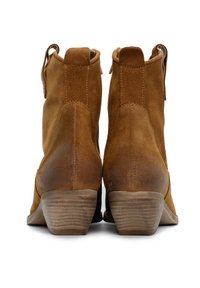 Stivaletti in suede marrone con finitura testurizzata, tacco basso impilato e linguette posteriori per una facile calzata, caratterizzati da una forma slanciata e affusolata.