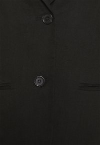 Blazer noir avec une texture lisse, col à revers cranté, fermeture à un bouton et deux ouvertures de poche discrètes à l'avant.