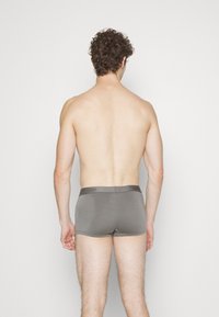 Boxer briefs grigi in cotone con una texture liscia, caratterizzati da un elastico con logo, mostrati di spalle.
