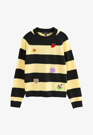 Żółty i czarny sweter w paski z naszywkami z haftem przedstawiającymi truskawkę, słonecznik, fioletową uśmiechniętą buzię, serce w tęczy oraz babeczkę.