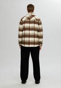 Rutet flannel skjorte i creme, brun og oliven, med krave, knapmanchetter og et afslappet fit, parret med sorte bukser.