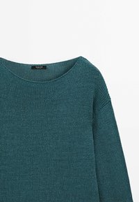 Pull en maille sarcelle à manches longues avec un col rond, montrant le haut devant et la manche droite sur fond blanc.