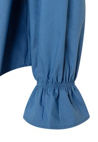 Blaue Baumwollbluse mit Ärmeln und gerafftem elastischen Saum, mit einer weichen Textur und einem ausgestellten Design am Bund. Glatte Stoffoberfläche.